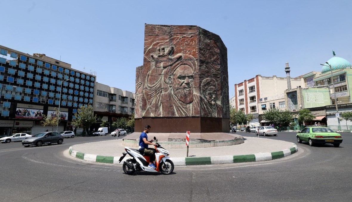 رجل إيراني يمر بدراجته النارية في ساحة انقلاب وسط العاصمة طهران (20 تموز 2021، أ ف ب). 