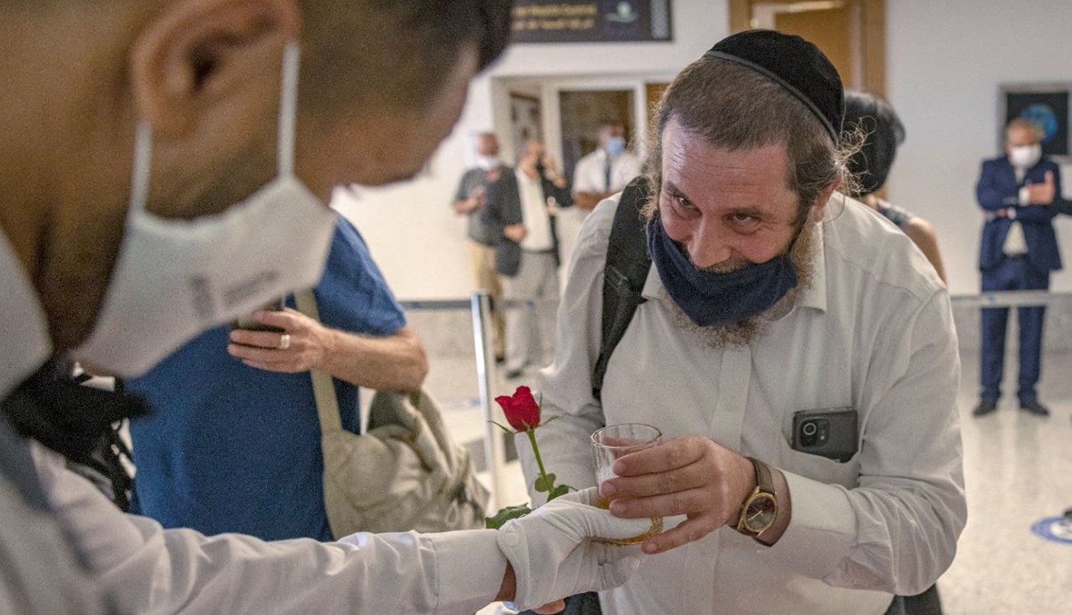 سائح إسرائيلي يتلقى وردة ومشروبًا ترحيبيًا لدى وصوله إلى مطار مراكش المنارة الدولي في أول رحلة تجارية بين المغرب وإسرائيل (25 تموز 2021، ا ف ب). 