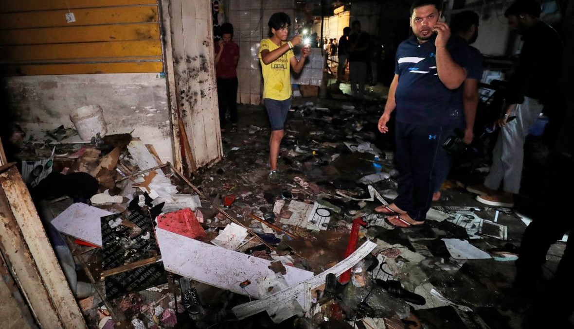 عراقيون يتفقدون موقع الانفجار في سوق شعبية في حي مدينة الصدر شرق بغداد (19 تموز 2021، أ ف ب). 