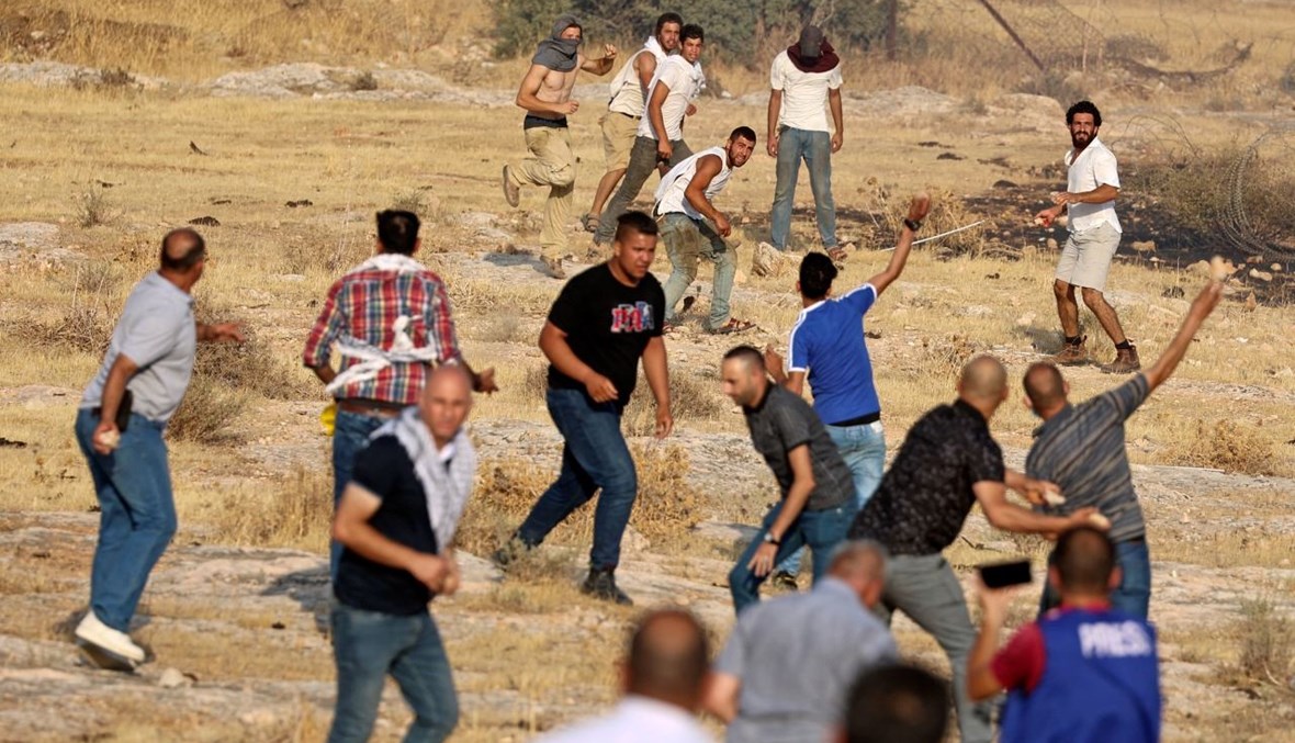 متظاهرون فلسطينيون يشتبكون مع مستوطنين إسرائيليين في معسكر للجيش الإسرائيلي تم إخلاؤه بالقرب من حاجز تياسير شرق طوباس شمال الضفة الغربية المحتلة (24 تموز 2021، أ ف ب). 