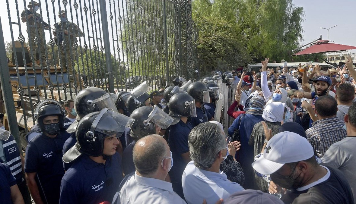 رجال أمن تونسيون يصدون أنصار حزب النهضة الإسلامي خلال احتجاج خارج مبنى البرلمان في العاصمة تونس (26 تموز 2021، أ ف ب).