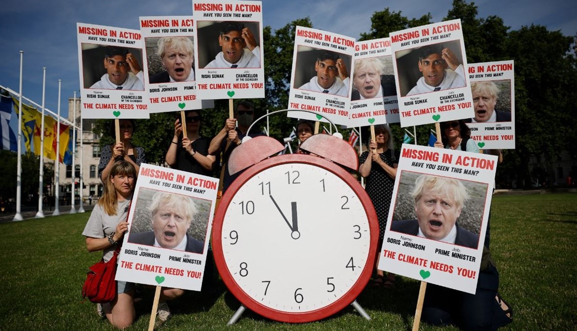 ناشطون يتظاهرون في ساحة البرلمان في لندن، للاحتجاج على السياسة الحكومية المتعلقة بالمناخ، قبل 100 يوم على قمة غلاسكو (23 تموز 2021، أ ف ب).