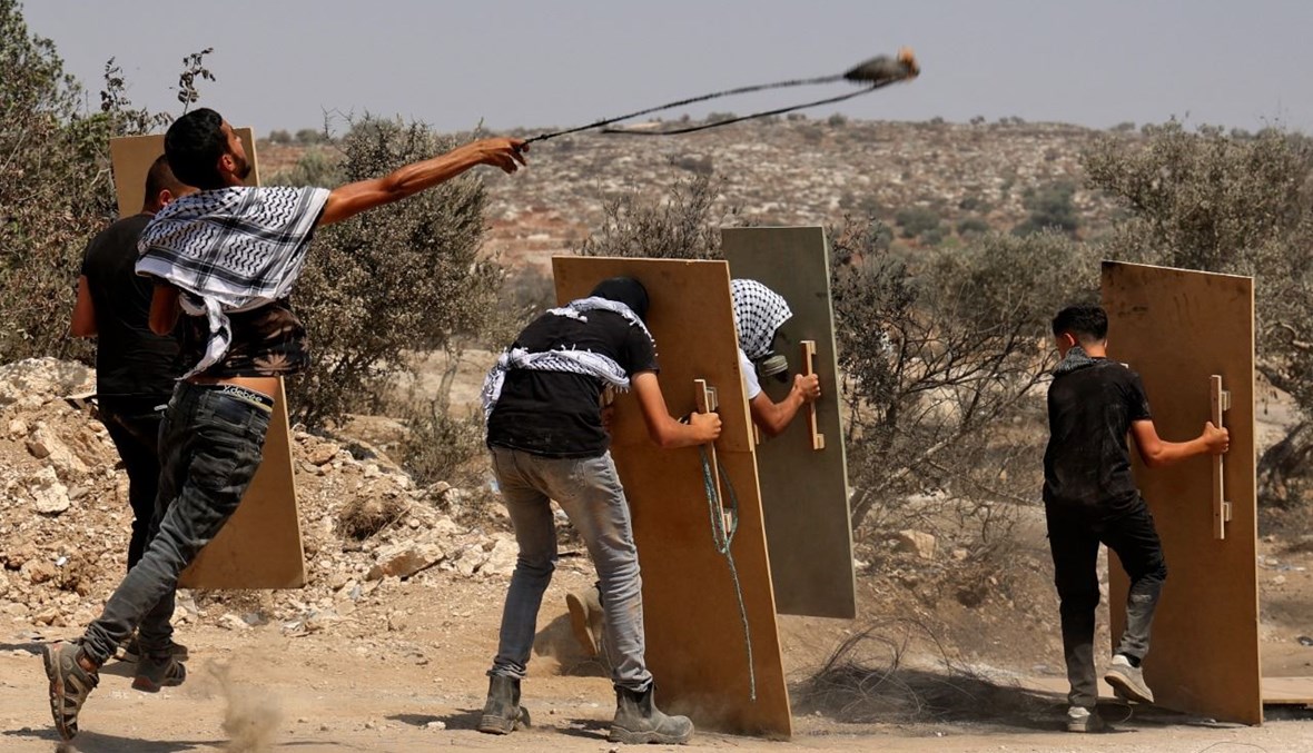 متظاهرون فلسطينيون يستخدمون الألواح الخشبية كدروع خلال اشتباكات مع القوات الإسرائيلية في قرية بيتا شمال الضفة الغربية المحتلة (6 آب 2021، أ ف ب). 