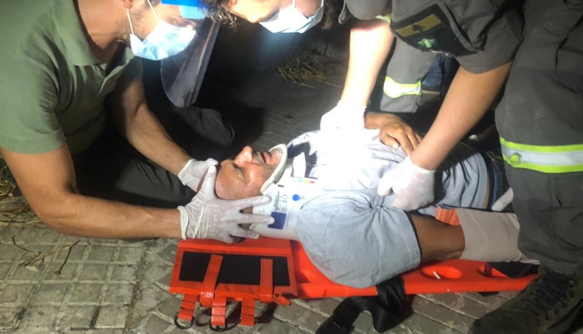 عناصر الدفاع المدني خلال إسعافهم الزميل المصوّر حسام شبارو بعد الاعتداء عليه في محيط عين التينة (نبيل اسماعيل).