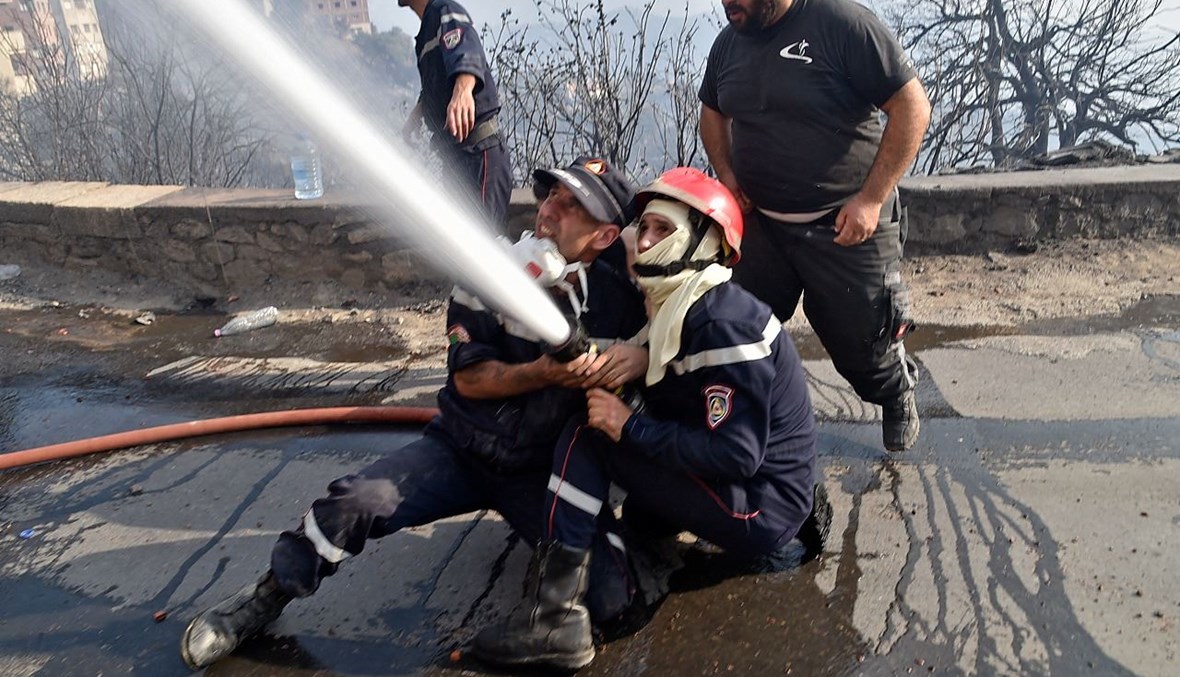 رجال إطفاء يكافحون النيران في التلال الحرجية بمنطقة القبائل  شرق العاصمة الجزائر (11 آب 2021، أ ف ب). 