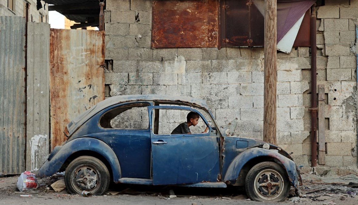 طفل فلسطيني يلعب داخل سيارة قديمة في مدينة غزة (5 آب 2021، أ ف ب). 