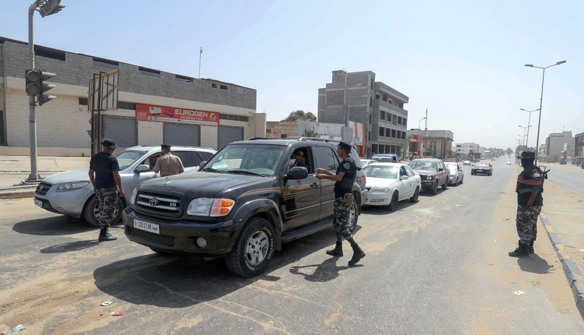 رجال أمن ليبيون وقفوا عند نقطة تفتيش في طرابلس، للتحقق من تنفيذ حظر التجول الكامل الذي أعلنته السلطات (7 آب 2021ـ ا ف ب).