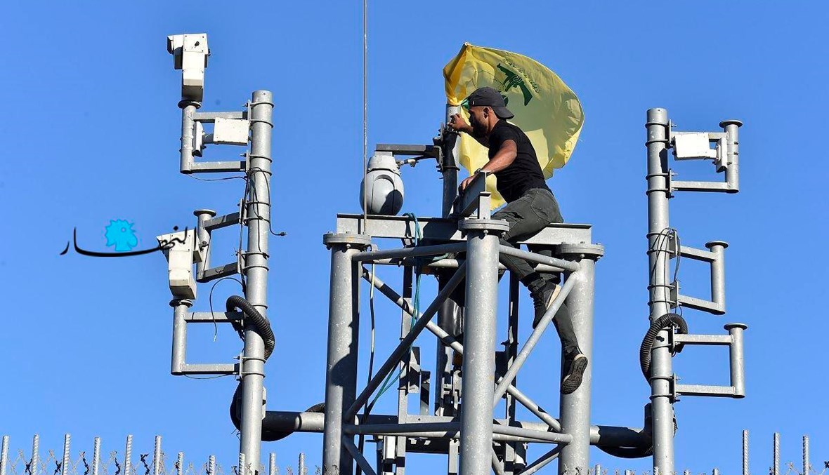مناصر لـ"حزب الله" يتسلّق برج كاميرات المراقبة عند الحدود اللبنانية الجنوبية (حسام شبارو).