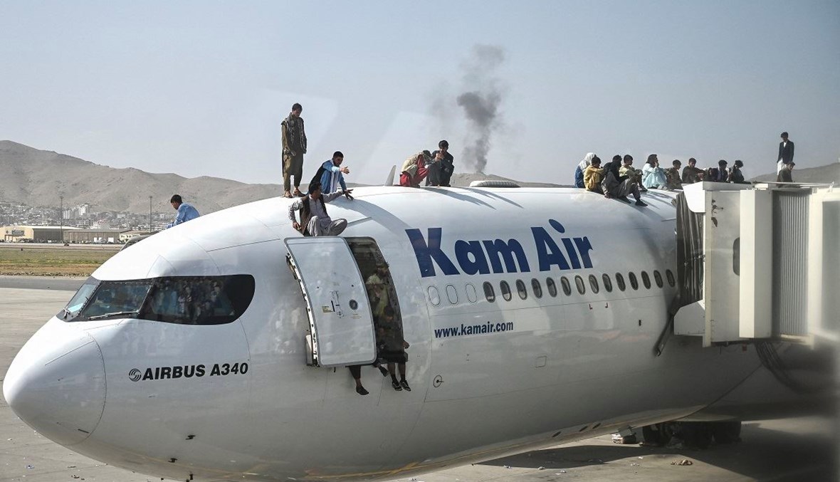 مواطنون أفغان يتسلّقون طائرة في مطار كابول (أ ف ب).