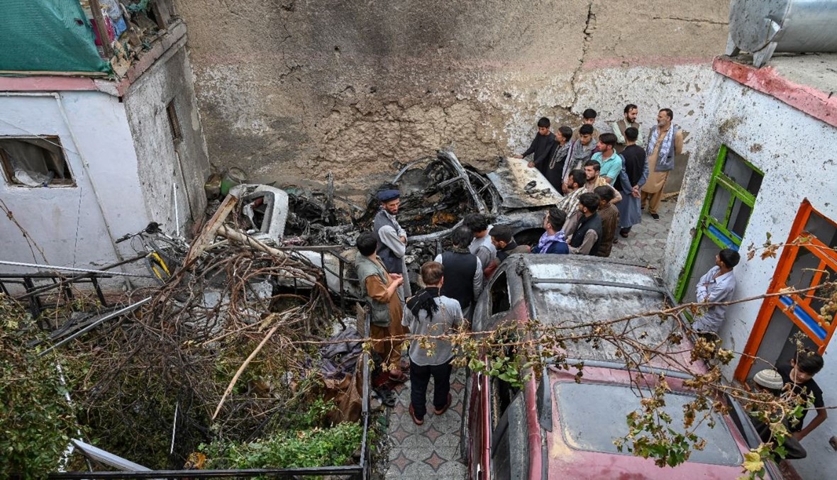 سكان أفغان تجمعوا بجوار سيارة مدمرة قرب منزل، بعد يوم على غارة جوية أميركية في كابول (30 آب 2021، أ ف ب). 
