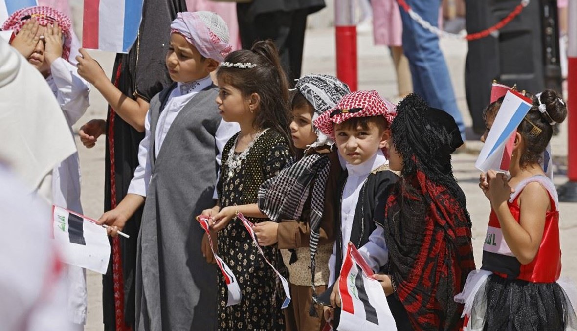 أطفال يرتدون اللباس الفولوكلوري العراقي خلال استقبال ماكرون في الموصل (أ ف ب).