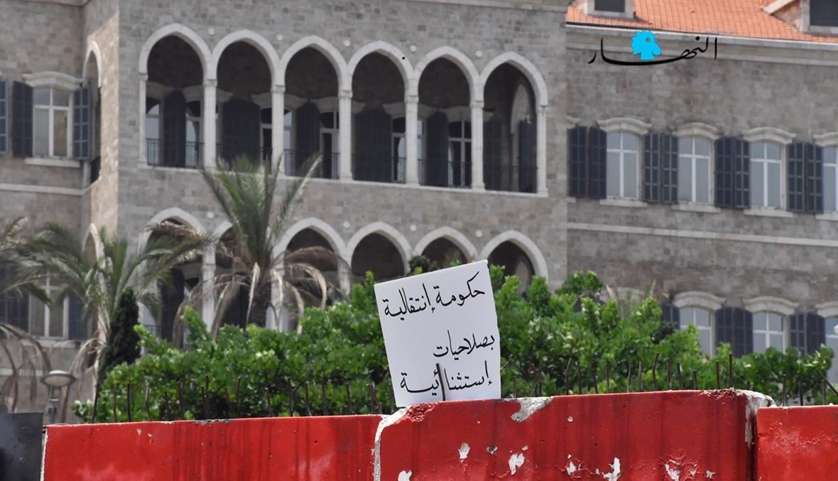 لافتة وضعها محتجّون على الحائط الفاصل أمام السرايا الحكومية تطالب بـ"حكومة انتقالية بصلاحيات استثنائية" (تعبيرية- نبيل إسماعيل).