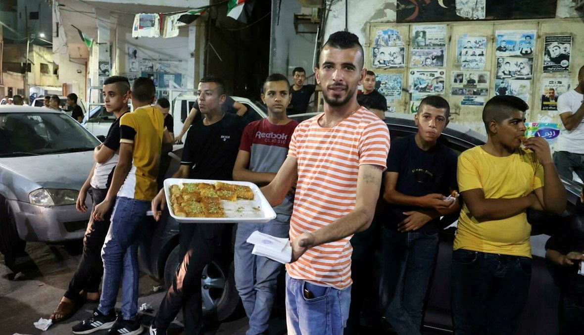 شاب فلسطيني يوزع الحلوى ابتهاجاً بفرار ستة معتقلين أمنيين من سجن جلبوع (أ ف ب).