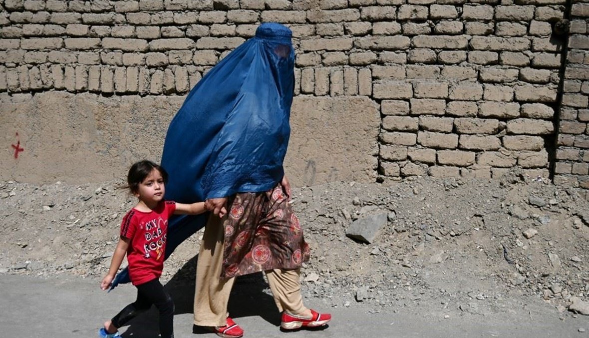 امرأة مع طفلة في شارع بكابول أمس (أ ف ب).