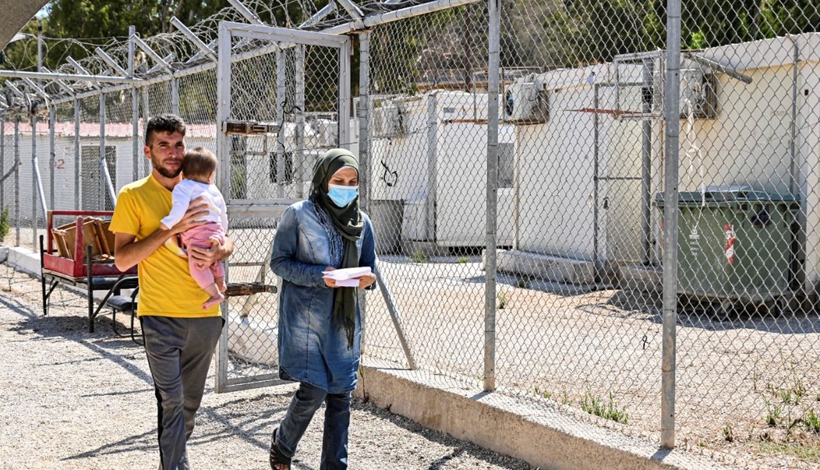 عائلة تمشي في مخيم للمهاجرين في جزيرة ليروس اليونانية (7 ايلول 2021، أ ف ب). 