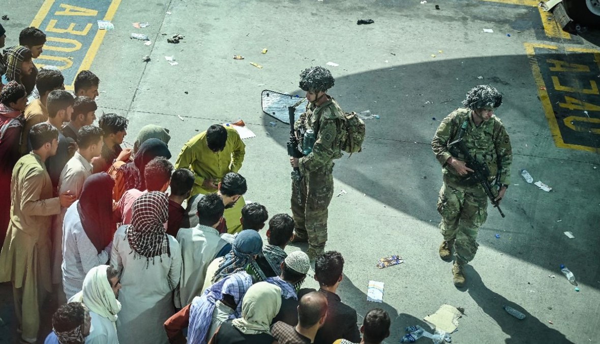 جنود أميركيون تأهبوا، بينما ينتظر أفغان في مطار كابول في كابول (أ ف ب).