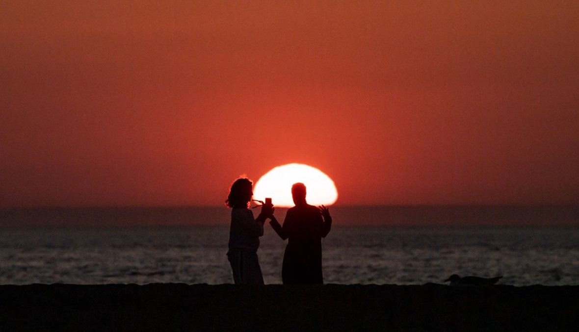 الناس ينظرون إلى غروب الشمس خلال مهرجان دوفيل السينمائي (أ ف ب). 