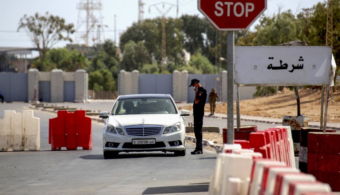 عنصر من الشرطة التونسية يدقق في أوراق مواطن ليبي عند نقطة حدودية في رأس جدير جنوب شرق تونس (17 ايلول 2021ـ ا ف ب). 