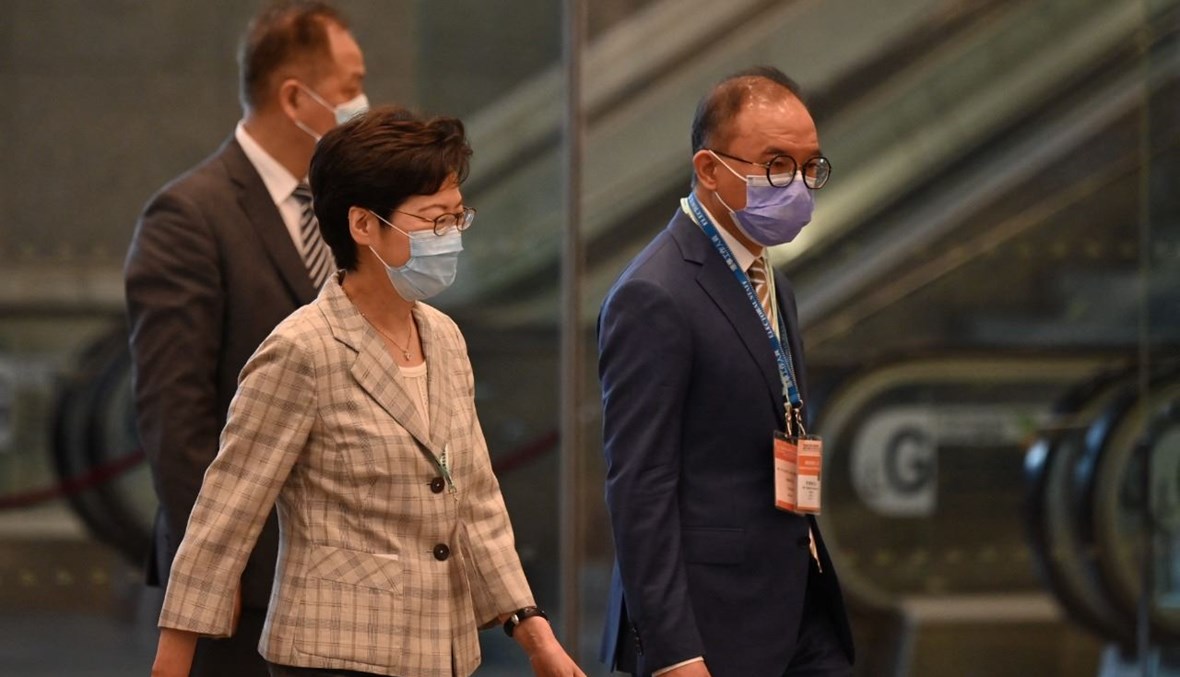 لام (الى اليسار) وسكرتير مكتب الشؤون الدستورية والبر الرئيسي إريك تسانغ يغادران مركز المؤتمرات والمعارض في هونغ كونغ حيث تجري عملية التصويت (19 ايلول 2021، أ ف ب). 