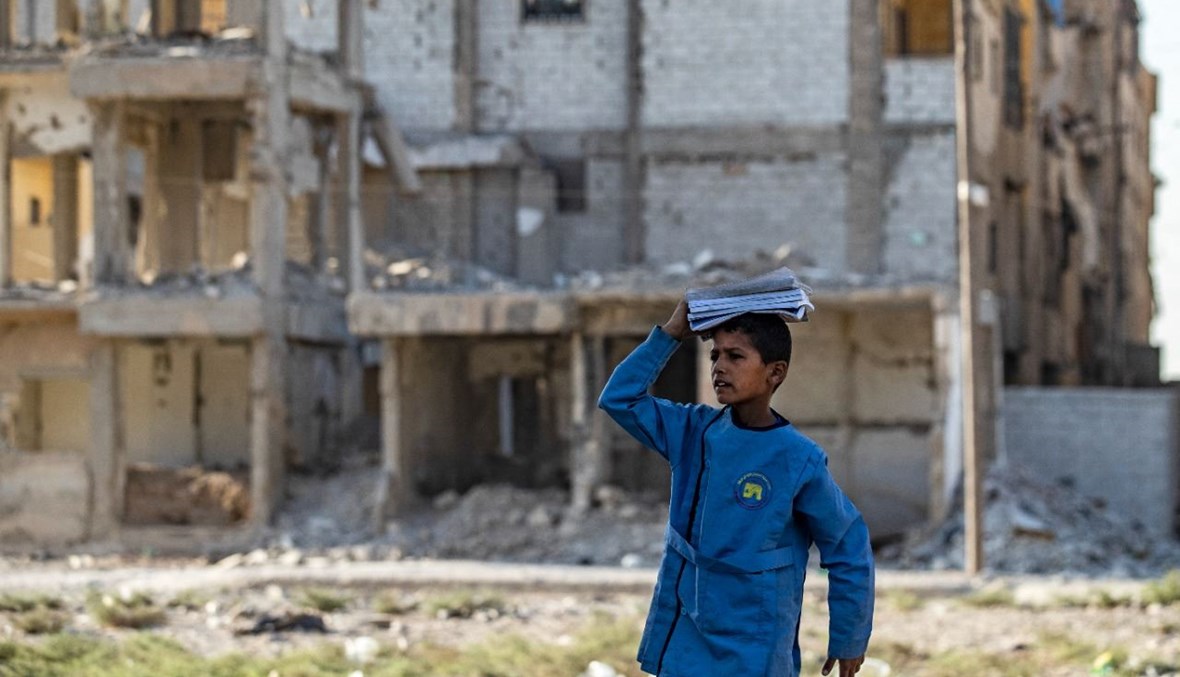 طالب سوري يمر قرب مبان متضررة في مدينة الرقة الشمالية خلال توجهه الى المدرسة (23 ايلول 2021، ا ف ب). 
