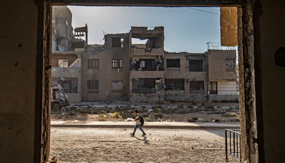 طالب سوري يمر قرب مبان متضررة في مدينة الرقة الشمالية خلال توجهه الى المدرسة (23 ايلول 2021، ا ف ب). 