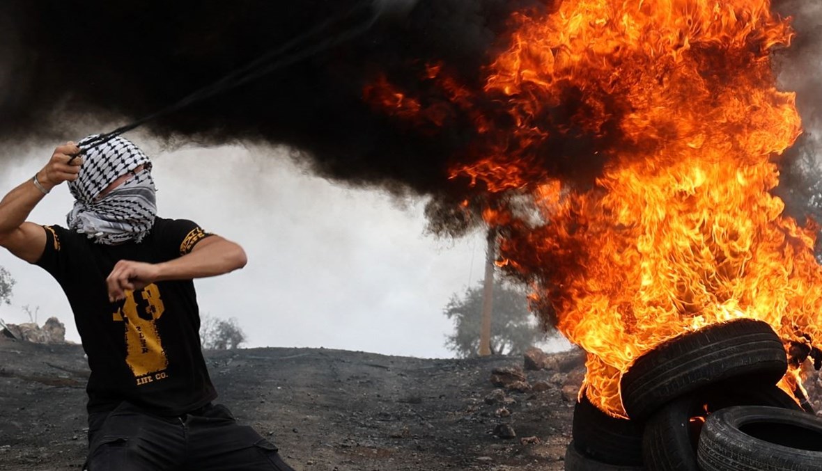 فلسطيني يقذف الحجارة خلال مواجهات مع قوات الأمن الإسرائيلية في أعقاب تظاهرة ضد المستوطنات في قرية بيتا بالضفة الغربية (24 ايلول 2021، أ ف ب). 