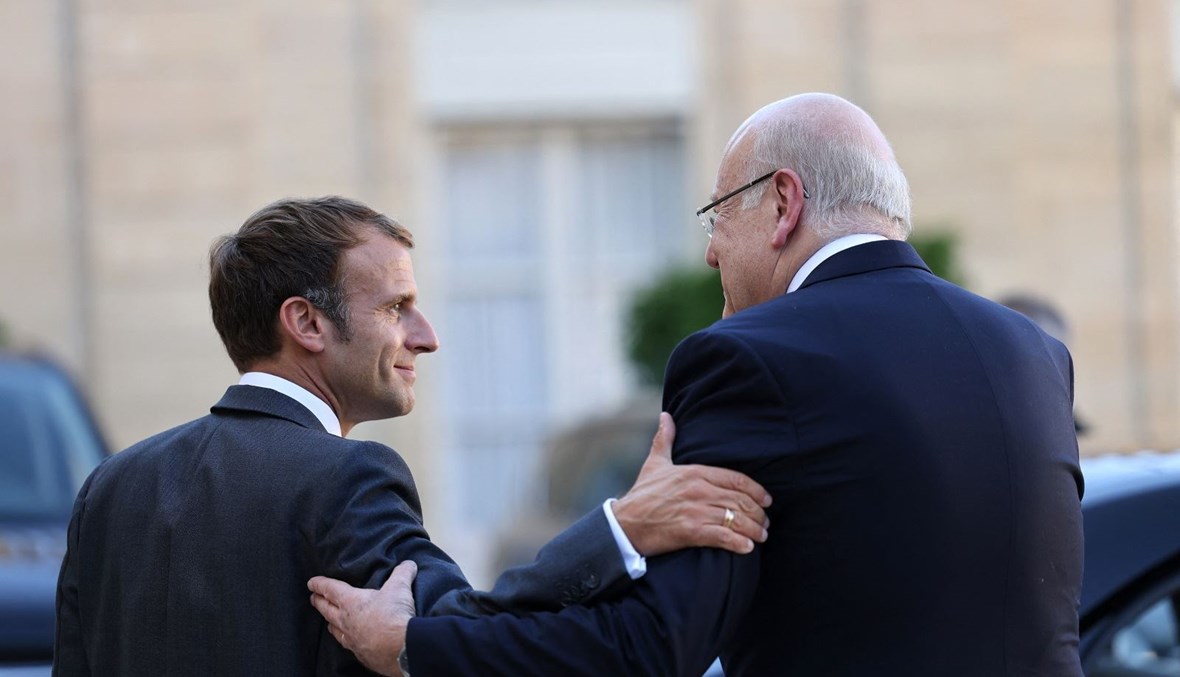 الرئيس الفرنسي إيمانويل ماكرون والرئيس نجيب ميقاتي في باحة قصر الإليزيه في باريس (أ ف ب).