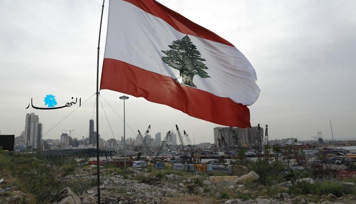العلم اللبناني مقابل أهراءات القمح في مرفأ بيروت المدمّر (مارك فياض).