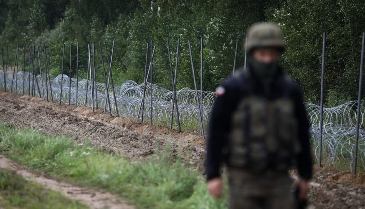 جندي بولوني وقف قرب سياج من الأسلاك الشائكة قيد الإنشاء على الحدود مع بيلاروسيا في زوبجيتسا فييركا في جوار بياليستوك شرق بولونيا (26 آب 2021، أ ف ب).