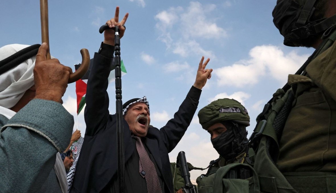 فلسطينيون يرددون هتافات أمام جنود إسرائيليين خلال تظاهرة في المنطقة الجنوبية من الخليل بالضفة الغربية، احتجاجا على مصادرة إسرائيل للأراضي وقطع إمدادات المياه عن القرى الفلسطينية (2 ت1 2021، أ ف ب). 