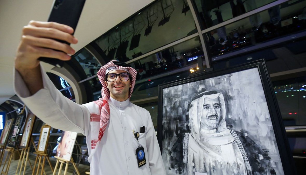 كويتي يلتقط "سيلفي" مع صورة للأمير الراحل الشيخ صباح الأحمد الجابر الصباح في معرض فني في مدينة الكويت، في الذكرى الأولى لوفاة الصباح (29 ايلول 2021، أ ف ب). 