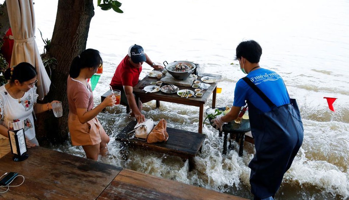 استمتاع بتناول الطعام وسيقانهم في الماء بمطعم في تايلاند.