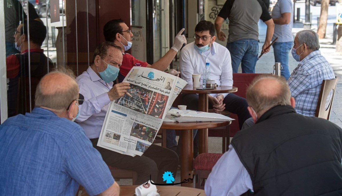 روّاد مقهى أحدهم يقرأ صحيفة "النهار" (نبيل اسماعيل).