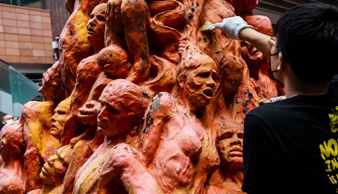 عضو في اتحاد طلاب جامعة هونغ كونغ ينظف التمثال الذي يكرم ضحايا القمع الصيني لتظاهرات ساحة تيان انمين عام 1989 (4 حزيران 2021، أ ف ب).