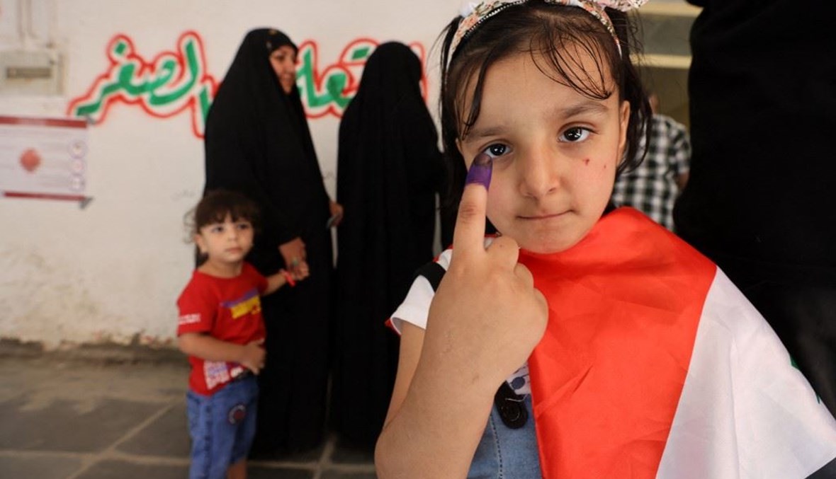 طفلة عراقية ترفع إصبعها بدلالة على مشاركتها رمزيّاً في الانتخابات العراقية (أ ف ب).