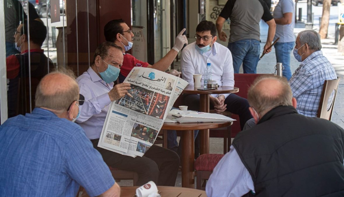 Un homme lit le journal Annahar dans un café (Nabil Ismail).