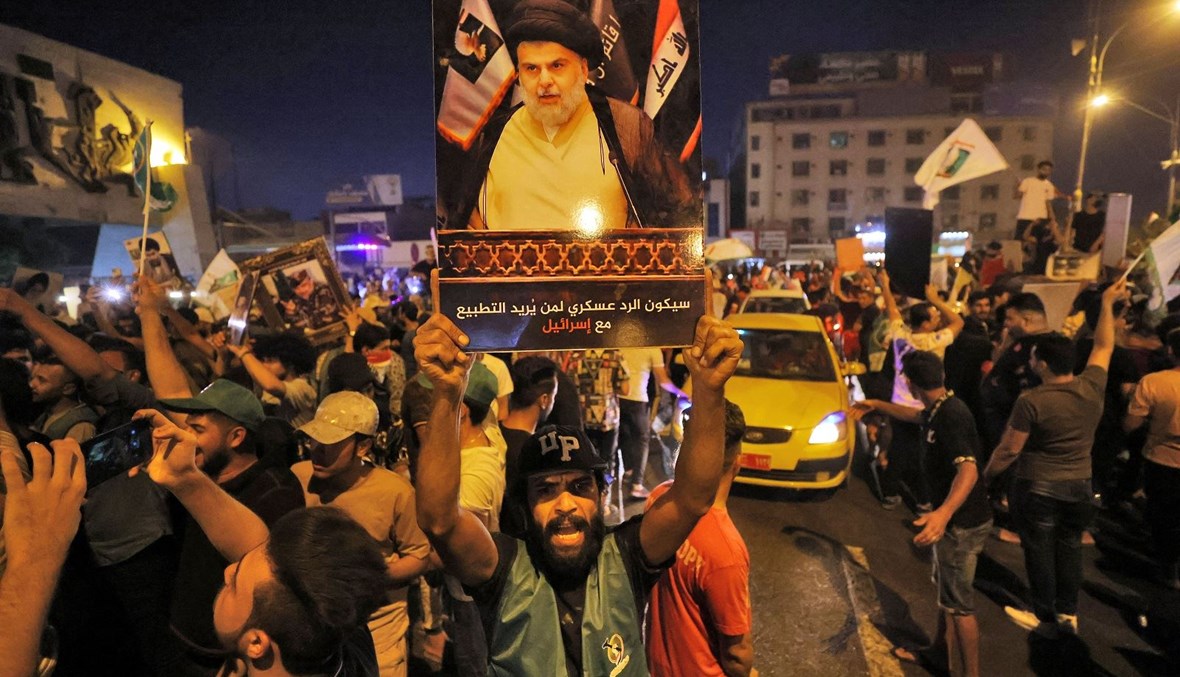 مناصر لزعيم التيار الصدري مقتدى الصدر يرفع صورته بعد صدور نتائج الانتخابات في بغداد (أ ف ب).