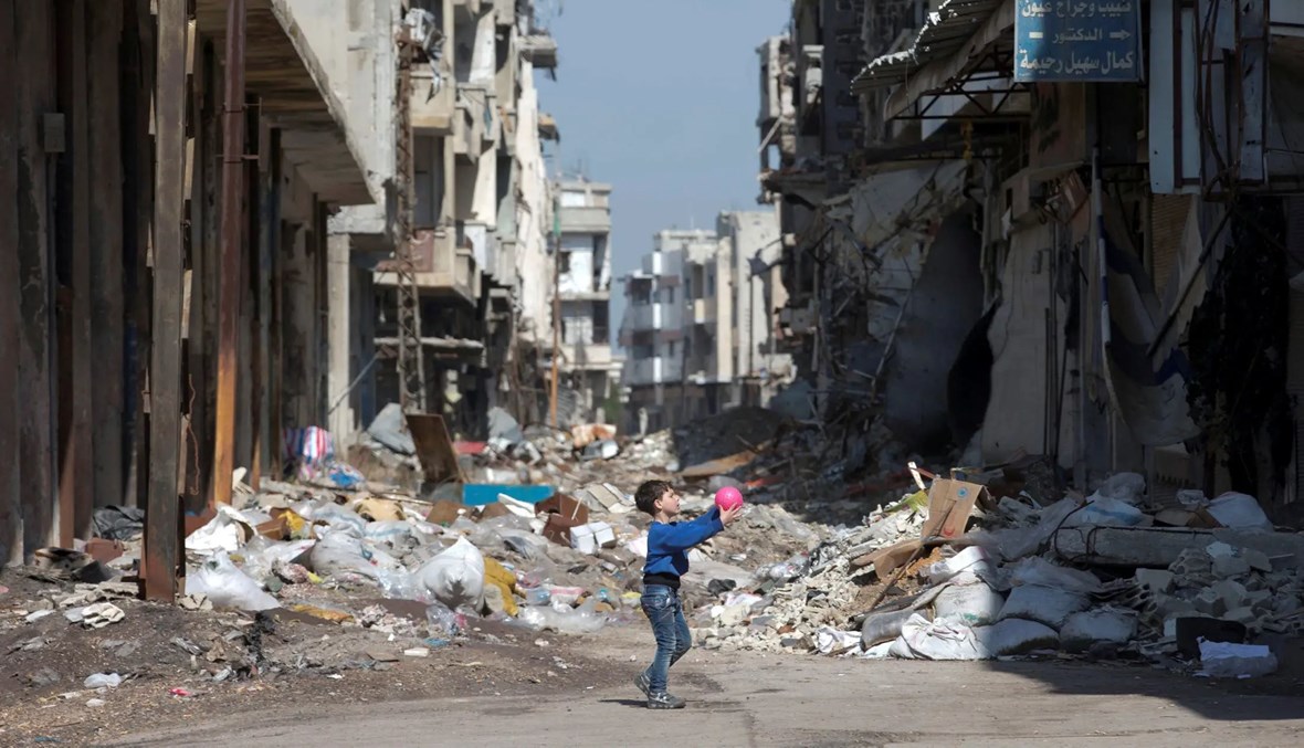 طفل يلعب بالكرة في أحد أحياء حمص المدمّرة (أ ف ب).