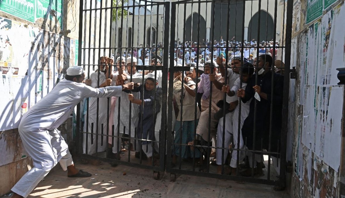 محتجون يحاولون كسر بوابة مغلقة للمسجد الوطني خلال تظاهرة بعد صلاة الجمعة في دكا (15 ت1 2021، أ ف ب). 