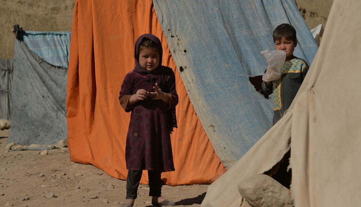 طفلان يقفان بجوار خيام في مخيم مؤقت بالقرب من طريق سريع بين هارت وبادغيس في أفغانستان (14 ت1 2021، أ ف ب).