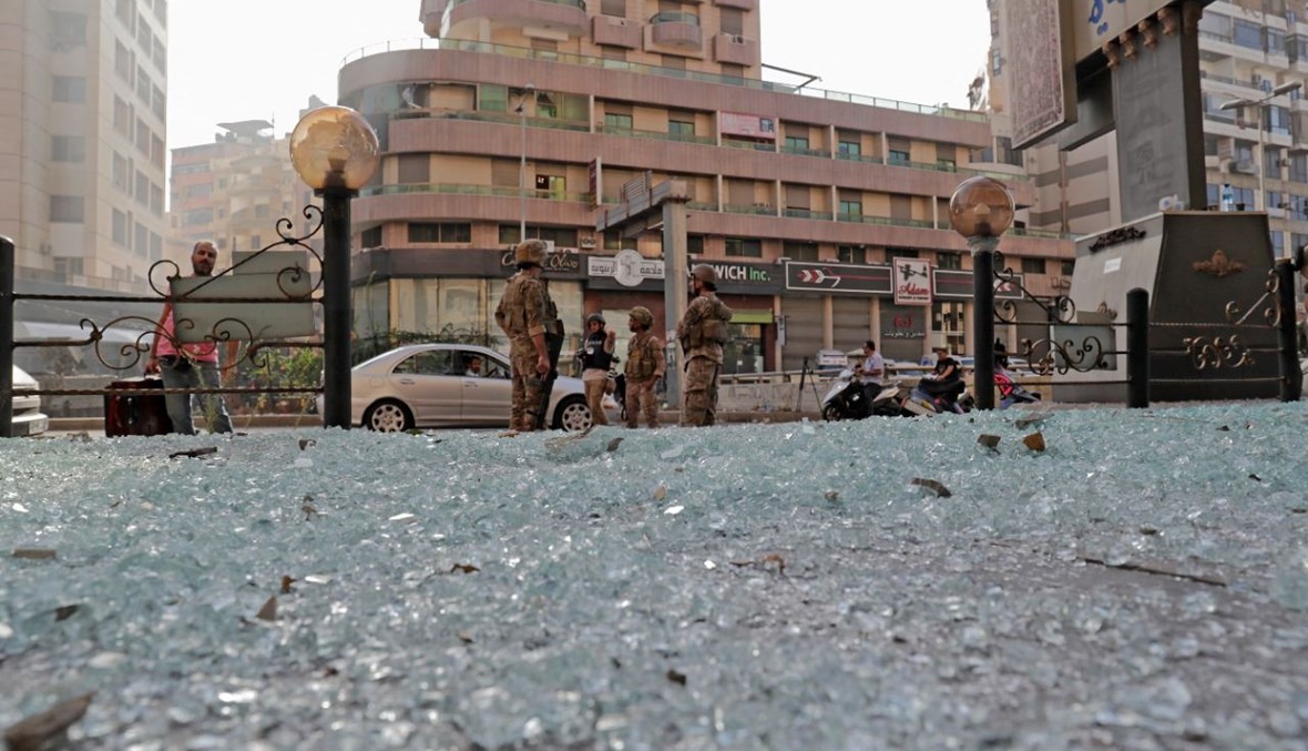 جنود من الجيش اللبناني انتشروا بالقرب من شارع غطى الزجاج المكسور الطريق وسط اشتباكات في منطقة (14 ت1 2021، أ ف ب). 