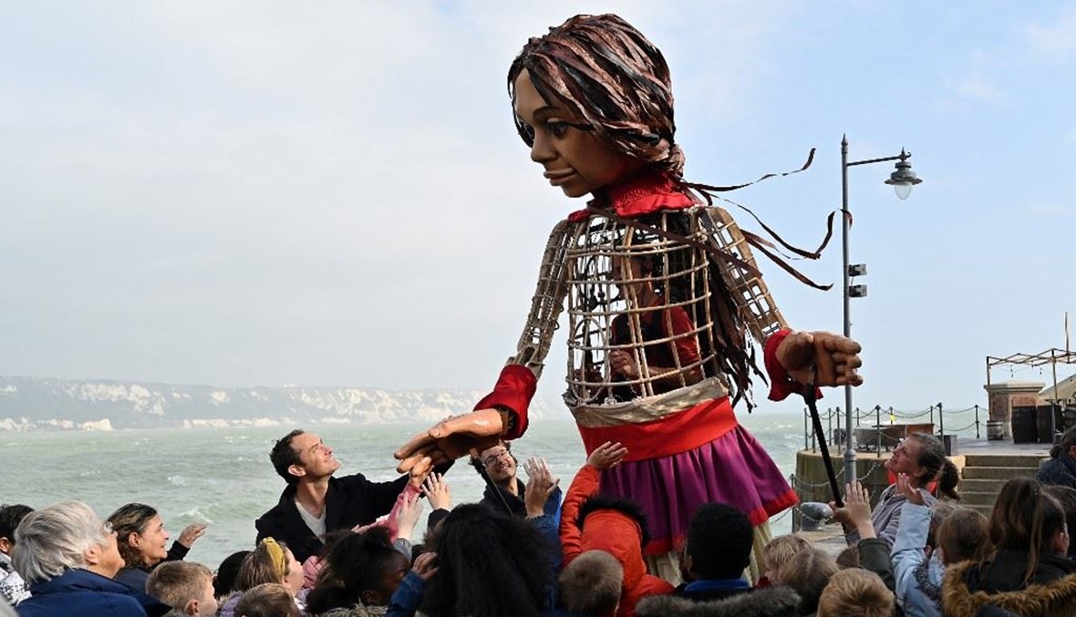 الفنان جود لو يمسك بيد "ليتل أمل" دمية عملاقة تصوّر فتاة سورية لاجئة (أ ف ب). 