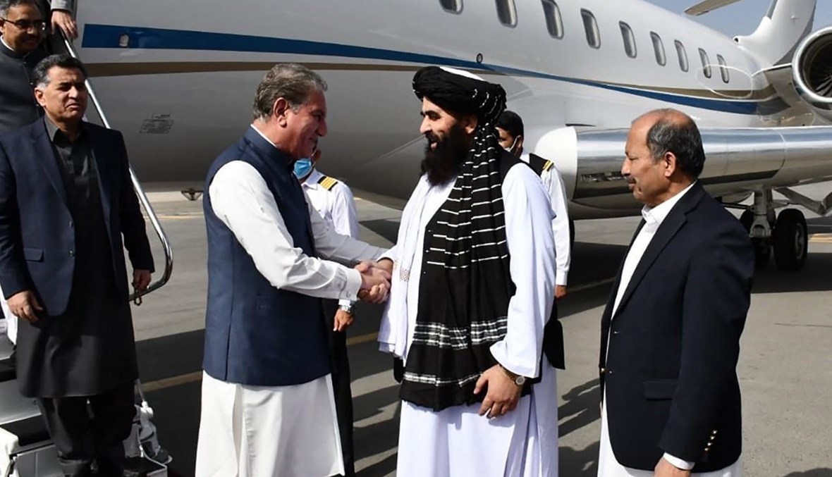 متقي (الى اليمين) مستقبلا قرشي لدى وصوله إلى المطار في كابول (21 ت1 2021، أ ف ب). 