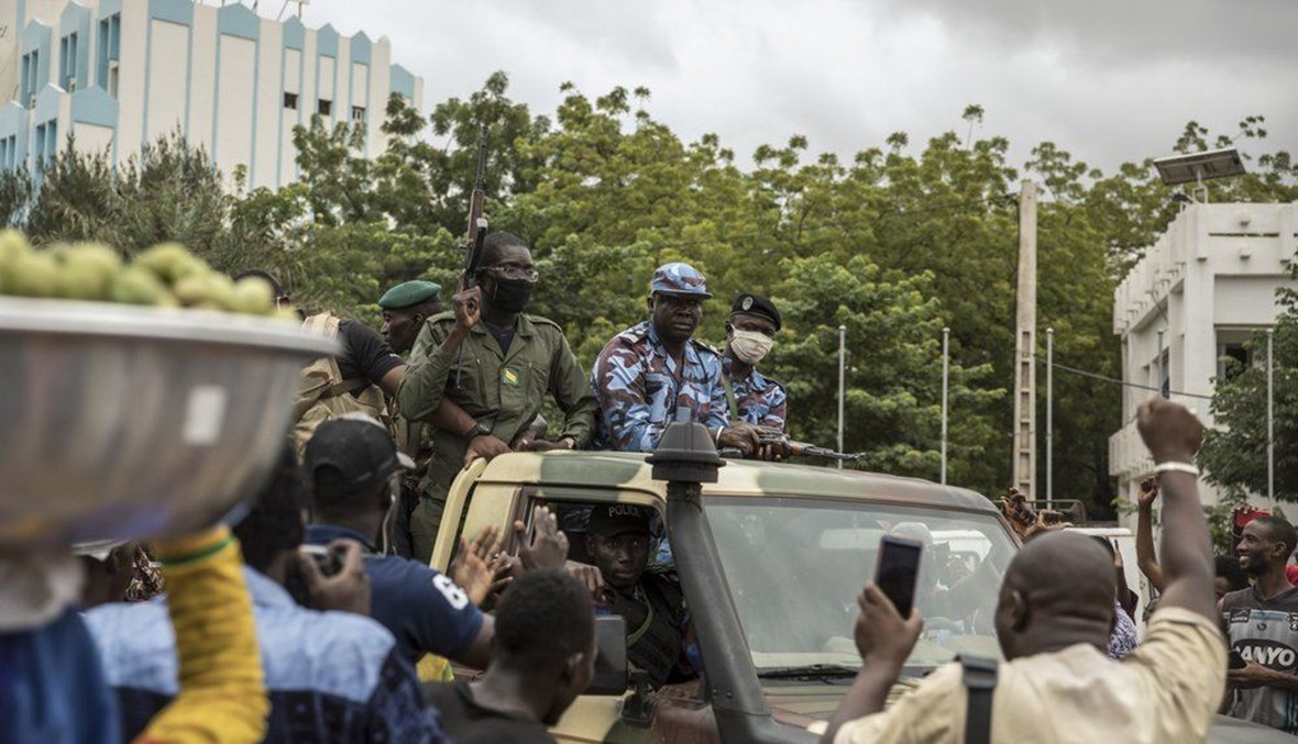 أشخاص يحتفلون خلال مرور قوات الأمن في باماكو بعد يوم على إطلاق جنود مسلحين النار في الهواء خارج منزل الرئيس إبراهيم بوبكر كيتا واحتجازه (19 آب 2020، أ ب). 