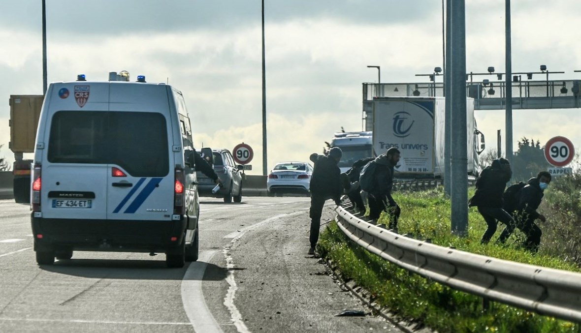 مهاجرون يهربون من دورية للشرطة على طريق بالقرب من كاليه في فرنسا (5 ت2 2021، أ ف ب). 