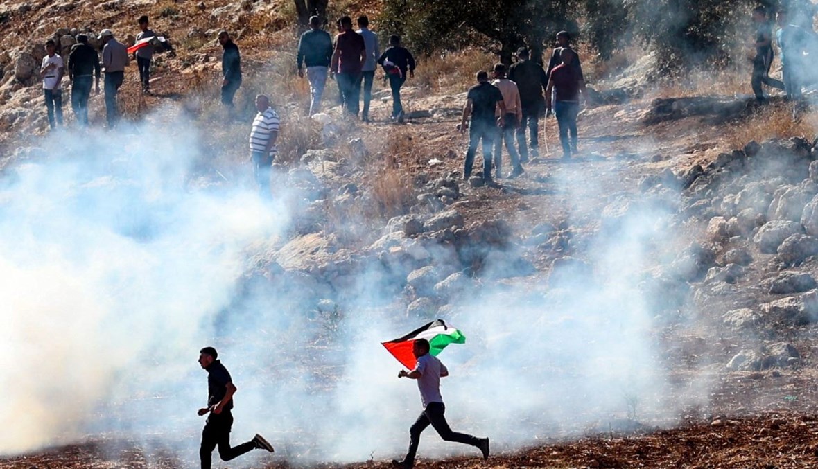 فلسطينيون يواجهون قوات الأمن الإسرائيلية خلال تظاهرة ضد إقامة البؤر الاستيطانية الإسرائيلية على الأراضي الفلسطينية، في بيت دجن شرق نابلس بالضفة الغربية المحتلة (5 ت2 2021، أ ف ب). 