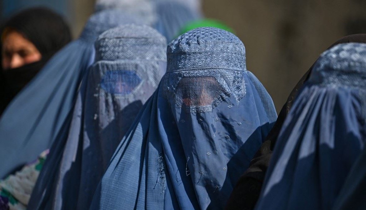 نساء يرتدين البرقع ينتظرن في طابور أثناء توزيع الغذاء لبرنامج الغذاء العالمي في ضواحي كابول (أ ف ب).