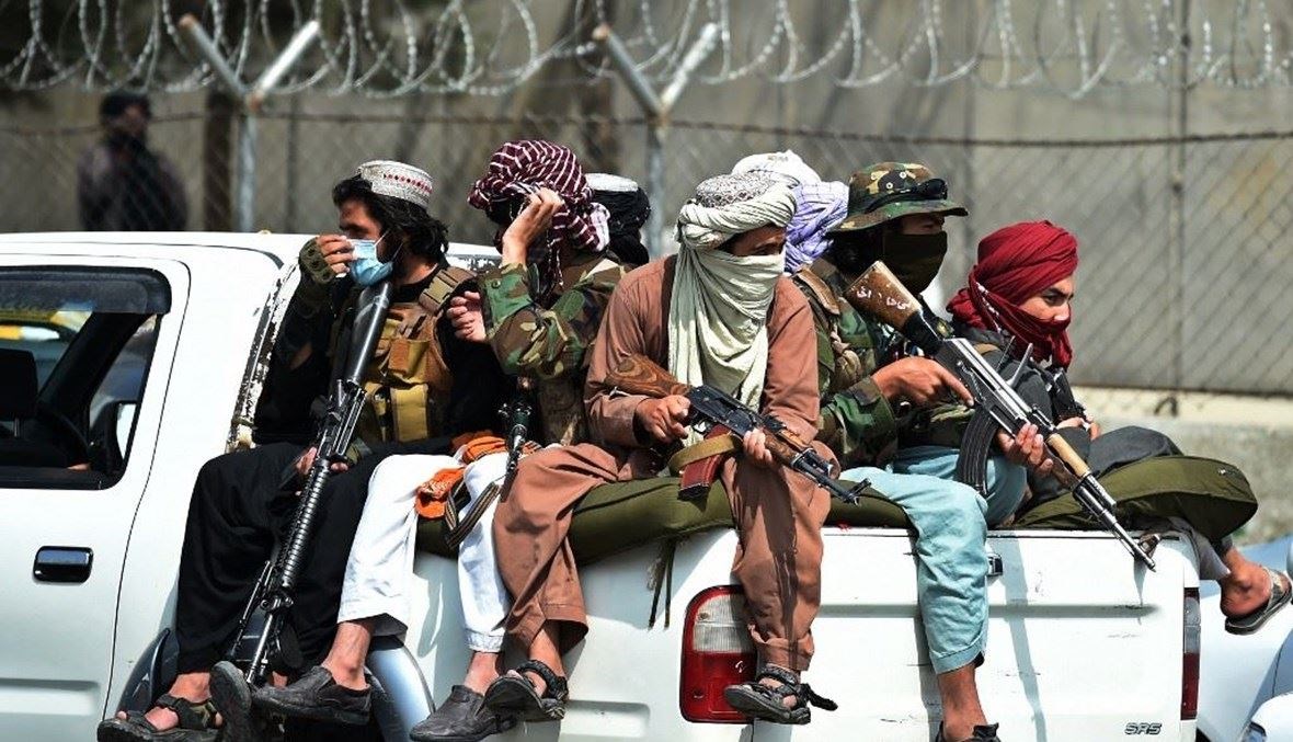مقاتلون من "طالبان" أمام سور مطار كابول (أ ف ب).