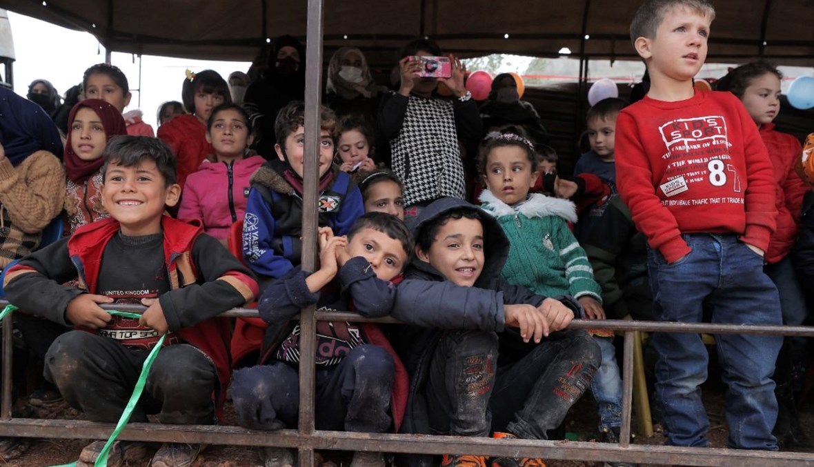 أطفال يحضرون عرضا مسرحيا في الهواء الطلق في مخيم حرنبوش للنازحين السوريين في شمال محافظة إدلب في شمال غرب سوريا في اليوم العالمي للطفل (20 ت2 2021، أ ف ب). 