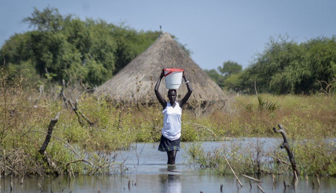 امرأة تحمل دلوًا على رأسها وهي تمشي وسط سيول تجمعت في قرية وانغ تشوت بمقاطعة فنجاك القديمة في ولاية جونقلي جنوب السودان (26 ت2 2020، أ ب). 